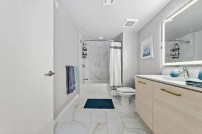a white bathroom with a shower and a toilet at Amber Drift - Santa Monica 2BR Penthouse Ocean views in Los Angeles