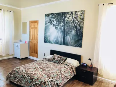 a bedroom with a bed and a large painting on the wall at Victorian Charm Meets Echo Park Vibes: Timeless Bungalow Retreat in Los Angeles