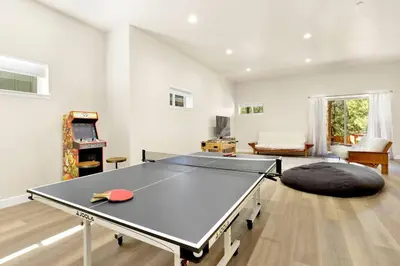 a ping pong table in a living room with a table at The Pines Retreat- Impeccable Modern Village Chalet in Big Bear Lake