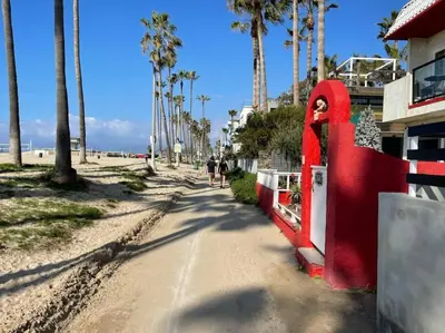 a road next to a beach with palm trees at House on The Beach in Los Angeles