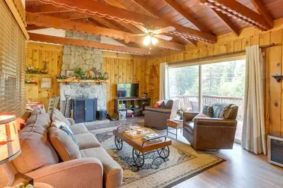 a living room with leather furniture and a stone fireplace at Crestline Cabin Close to Lake Arrowhead and Skiing in Crestline