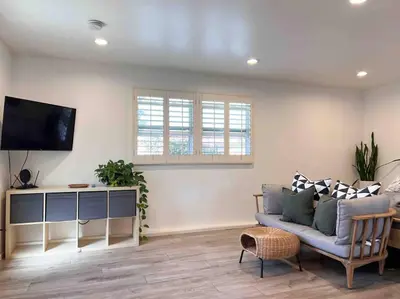 a living room with a couch and a flat screen tv at The Cozy Oasis - A Renovated and Modern Studio near LAX + SoFi + Beaches + Freeway in Lawndale