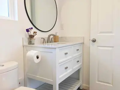 a white bathroom with a sink and a mirror at The Cozy Oasis - A Renovated and Modern Studio near LAX + SoFi + Beaches + Freeway in Lawndale
