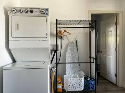 a white refrigerator in a room with a dress on a rack at The Cozy Oasis - A Renovated and Modern Studio near LAX + SoFi + Beaches + Freeway in Lawndale