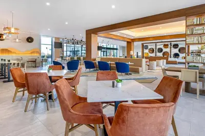 a dining room with tables and chairs in a restaurant at Cambria Hotel Burbank Airport in Burbank
