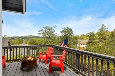 a deck with two red chairs and a fire pit at Charming Getaway Cabin in Lake Arrowhead