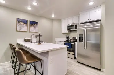 a kitchen with white cabinets and a stainless steel refrigerator at Fast WiFi and Free Parking Cozy Fontana Apartment in Fontana