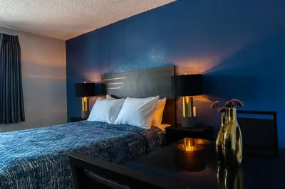 a hotel room with a bed with a blue wall at Pala Motel in Pomona