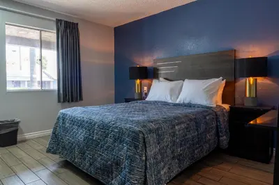 a bedroom with a bed with a blue wall at Pala Motel in Pomona