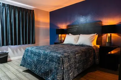 a bedroom with a bed with a blue wall at Pala Motel in Pomona