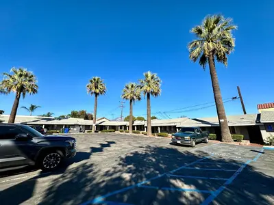 a car parked in a parking lot with palm trees at Pala Motel in Pomona