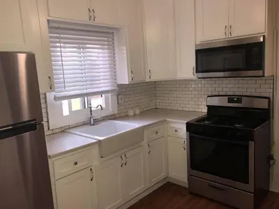 a kitchen with white cabinets and a sink and a stove at DTLA Oasis Private Bedroom with Exclusive Laundry - Steps to the Heartbeat of LA in Los Angeles