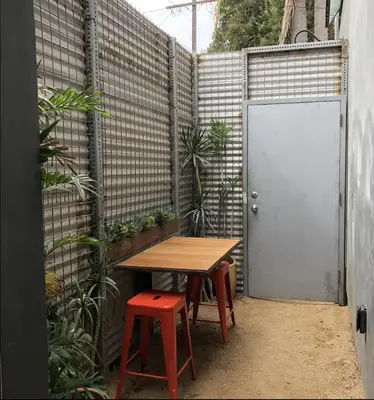 a table and stool in a courtyard with a fence at Dogtown Loft in Los Angeles