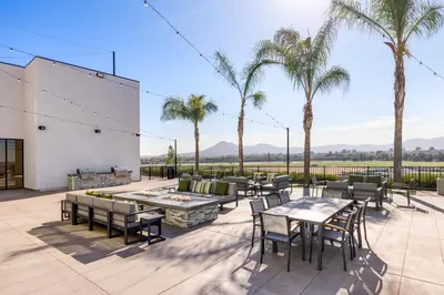 a patio with tables and chairs and palm trees at Staybridge Suites Eastvale - Norco by IHG in Eastvale