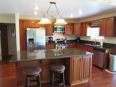 a kitchen with wooden cabinets and a large island with bar stools at Smith Lakefront Hideaway in Big Bear Lake