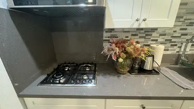 a kitchen counter with a stove and a vase of flowers at AB&B suite in Chino Hills