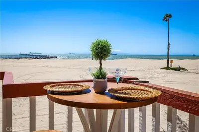 a table with two plates and wine glasses on the beach at Beachfront 3 Bedroom 3 Bath In Seal Beal, Ca in Seal Beach