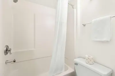 a white bathroom with a toilet and a shower at Studio 6 Suites Carpinteria, CA Santa Barbara South in Carpinteria
