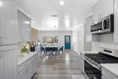 a kitchen with white cabinets and a table with chairs at Stylist Home In Convenient Location! in Temple City