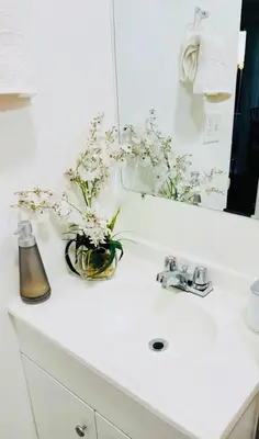 a bathroom sink with a vase of flowers on it at Wonderful LA studio apartment in Los Angeles
