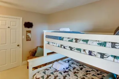 a bunk bed in a room with a chair at Spacious Crestline Retreat 1 Mi to Lake Gregory in Crestline
