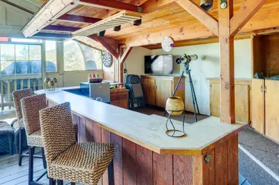 a kitchen with a bar with chairs and a camera at Spacious Crestline Retreat 1 Mi to Lake Gregory in Crestline