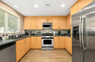 a kitchen with wooden cabinets and stainless steel appliances at The Coral Loft - Marina Bliss Water view 2BR Pool, Gym in Los Angeles