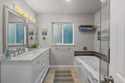 a white bathroom with two sinks and a tub at On the Boardwalk in Long Beach