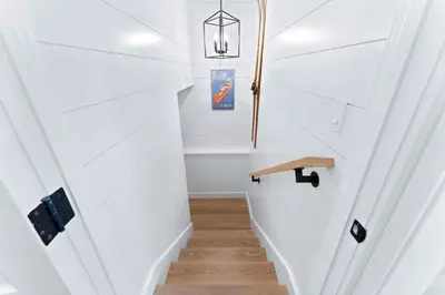 a hallway with white walls and a staircase with a wooden table at Majestic Lakeview Lodge in Lake Arrowhead