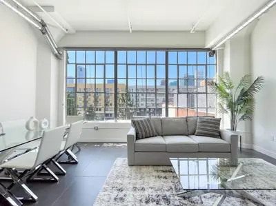 a living room with a couch and a large window at Modern Loft in DTLA - Rooftop Pool & Free Parking! in Los Angeles
