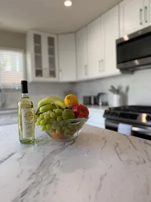 a bowl of fruit on a counter with a bottle of wine at Coastal Escape in Redondo Beach in Redondo Beach