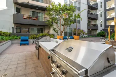 a barbecue on a patio with a building in the background at MDR Studio Apartment Luxury pool, gym, parking, jacuzzi. in Los Angeles