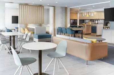 a restaurant with tables and chairs and a kitchen at TownePlace Suites by Marriott Monrovia in Monrovia
