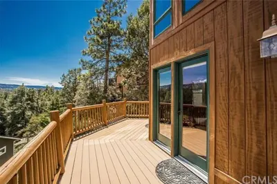 a wooden deck with glass doors on a house at Peaceful Cabin Home with Breathtaking View! in Big Bear City