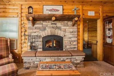a living room with a fireplace in a log cabin at Peaceful Cabin Home with Breathtaking View! in Big Bear City