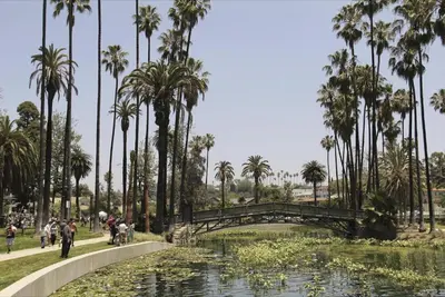 a bridge over a pond with palm trees in a park at Spacious Resort Getaway @ Echo Park Ranch - Luxury indoor/ outdoor home steps from Sunset Blvd, Echo Park Lake, Dodgers Stadium in Los Angeles