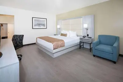 a hotel room with a bed and a blue chair at Ramada by Wyndham Burbank Airport in Burbank