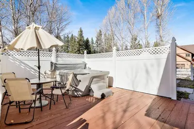 a patio with a table and an umbrella on a white fence at Divine Chateau Big Bear~ Hot Tub~ Walk to Lake~ in Big Bear Lake