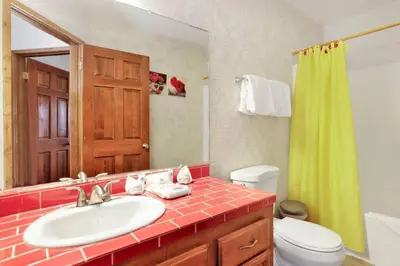 a bathroom with a sink and a toilet and a mirror at The Octagon Big Bear~ Hot Tub~ Pool Table~Views in Big Bear City