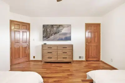 a bedroom with two beds and a dresser and two doors at The Octagon Big Bear~ Hot Tub~ Pool Table~Views in Big Bear City