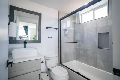 a bathroom with a shower and a toilet and a sink at Normandie Hostel in Los Angeles
