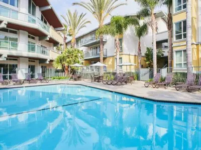 a swimming pool in front of a building with palm trees at The Moonstone - Cozy Marina side Garden View Pool and Gym in Los Angeles