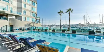 a swimming pool with lounge chairs and a building at Harbor Views Retreat By Venice Beach In Marina DR in Los Angeles