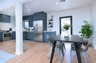 a kitchen with blue cabinets and a black table and chairs at Beautiful 3 Bed Home with a Large Back Yard Outdoor Space in Los Angeles