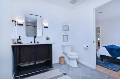 a bathroom with a toilet and a sink with a mirror at Beautiful 3 Bed Home with a Large Back Yard Outdoor Space in Los Angeles