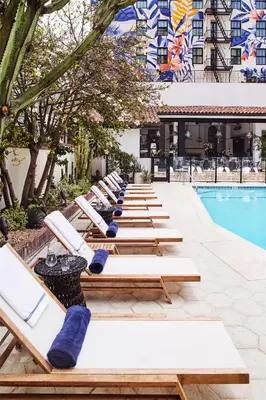 a row of lounge chairs next to a pool at Hotel Figueroa, Unbound Collection by Hyatt in Los Angeles