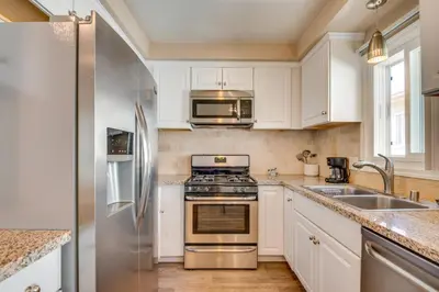 a kitchen with white cabinets and a stainless steel refrigerator at LA Condo about 1 Mi to The Kia Forum and SoFi Stadium in Inglewood