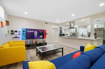a living room with a blue couch and a tv at Gamers Getaway by OC Adventure Homes in Stanton