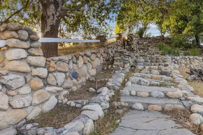 a stone retaining wall with stone steps and a tree at The Magic Castle (Unit5) - Six Flags in Newhall
