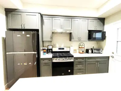 a kitchen with white cabinets and a black refrigerator at Incredible Value for 12 guests, New 3BR Home by Disneyland, Knott's, Beach in Midway City
